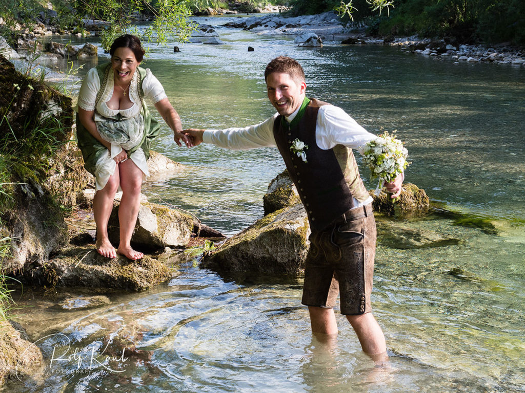 Brautpaar in Tracht im Wasser eines Gebirgsbaches
