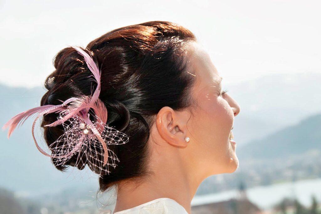 elegante Festtagsfrisur für dunkle Haare, hochgesteckt mit Federschmuck