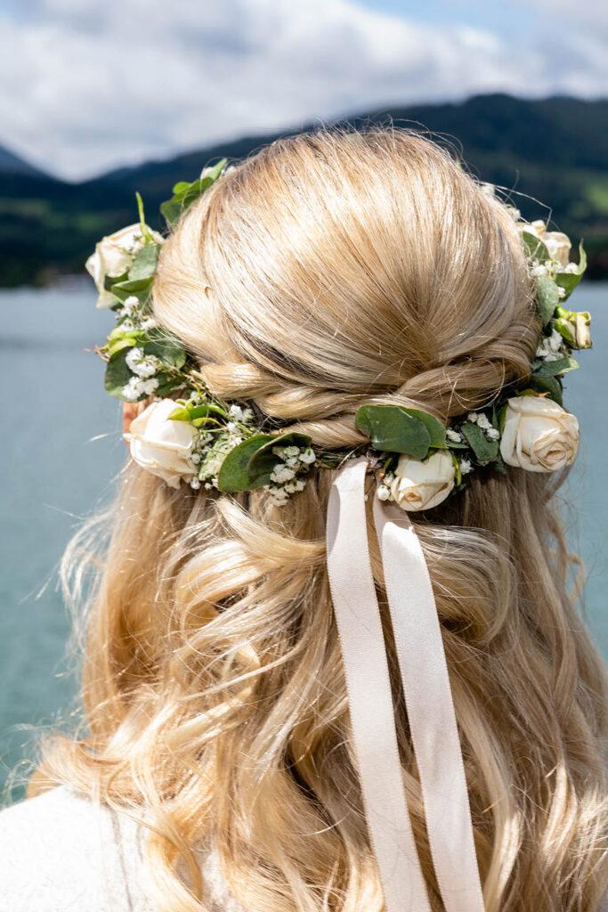 Festtagsfrisur für lange blonde Haare mit geflochtenem Zopf und Kranz aus Rosen